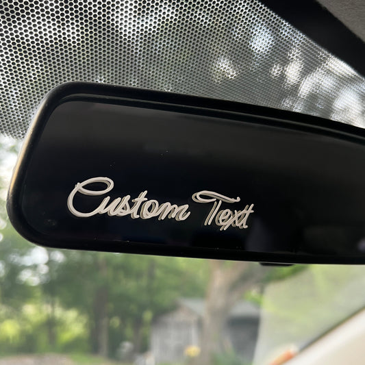 A Rear view mirror showing a vinyl decal sticker that says "Custom Text".